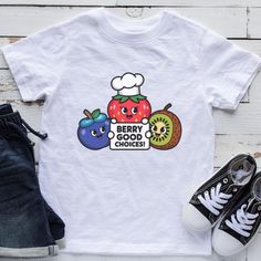 Encourage healthy eating with this adorable kids' t-shirt featuring fun cartoon fruits and the playful message, "Berry Good Choices!" This cute and colorful graphic tee is perfect for promoting nutrition and making healthy food choices fun for children. Ideal for parents, teachers, or health advocates, this shirt inspires kids to embrace fruits and healthy habits. A great gift for young food lovers, school events, or any occasion where promoting healthy lifestyles is important. Thank you for visiting my shop. Please contact me if you have any questions or requests. Not the design, colour or size you need? Each item is made individually so I can make anything you want. Just send a message with your ideas. This item is custom designed especially for you so I cannot accept returns but if you Cute Crew Neck T-shirt With Fruit Design, Cute White T-shirt With Fruit Print, Crew Neck Cotton T-shirt With Fruit Design, Cotton Crew Neck T-shirt With Fruit Design, Fun Short Sleeve T-shirt With Fruit Print, Fun White T-shirt With Fruit Print, Crew Neck Fruit Design Graphic Tee, Graphic Tee With Fruit Design And Crew Neck, Fruit Design Graphic Tee With Crew Neck