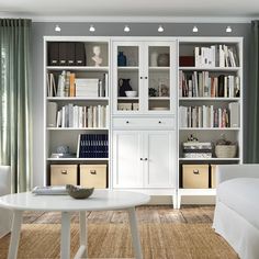 a living room filled with furniture and bookshelves next to a white couch in front of a window