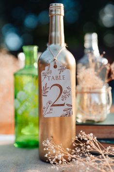 a bottle with a tag on it sitting next to some bottles and flowers in the background