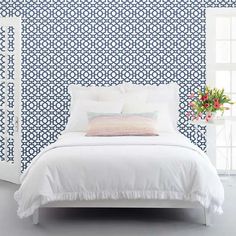 a white bed sitting in front of a blue and white wall with flowers on it