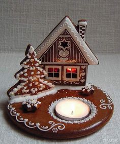 a lit candle sits in front of a gingerbread house