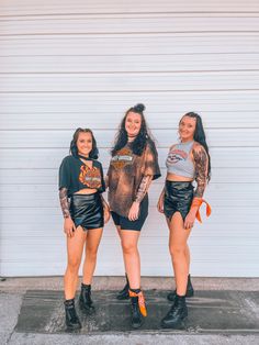 three girls standing next to each other in front of a garage door wearing matching outfits