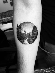 a man's arm with a black and white landscape tattoo on it