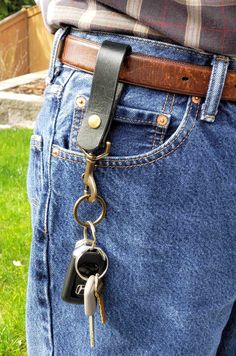 a person wearing jeans and holding two keys in their back pocket while standing on the grass