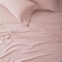 a bed with pink sheets and pillows on it