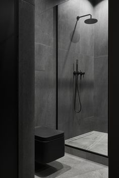 a bathroom with a black toilet and shower head in the corner, next to a walk - in shower