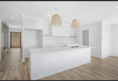 an empty kitchen with white cabinets and wood floors