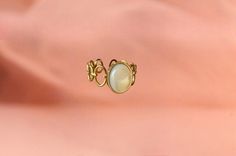 The ring is made from an original ring and a mother-of-pearl stone. The stone is oval and has a dimension of 1cm x 0.8 cm. The ring has a diameter of 1.6mm in diameter. Mother-of-pearl is a stone that produces calm, it has a beneficial effect on emotions and promotes the circulation of energy. It is adjustable to fit all fingers. My jewelry is handmade from materials and fine stones carefully selected in my workshop in Paris. Each stone is natural and unique and may therefore have color variatio Gold Cabochon Moonstone Ring, Vintage Metal Crystal Ring, Elegant Brass Moonstone Ring, Unique Pearl Promise Ring, Vintage Pearl Ring With Gemstone, Elegant Opal Ring With Moonstone, Elegant Brass Rings With Cabochon, Gold Mother Of Pearl Ring For Gift, Elegant Mother Of Pearl Ring As Gift