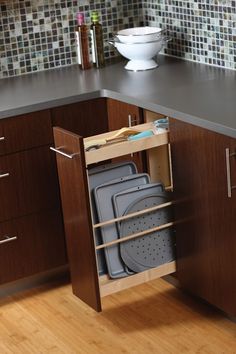 an open cabinet in the middle of a kitchen with pots and pans on it