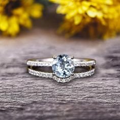 a close up of a ring on a wooden surface with flowers in the back ground