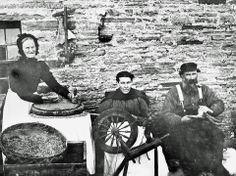 an old black and white photo of three people sitting in front of a stone building