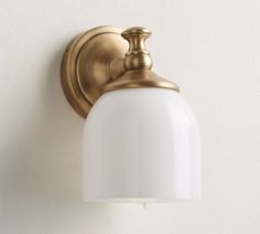 a light fixture mounted on the wall with a white glass shade hanging from it's side