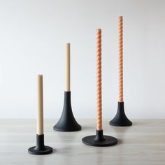 three black and orange candles are on the floor next to each other, with one candle sticking out of it's base