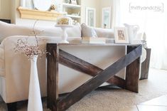 a living room with a white couch and wooden table in the centerpiece on carpeted flooring