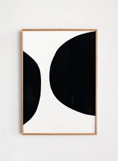 a black and white painting hanging on a wall next to a wooden framed art piece