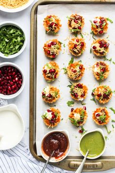 small appetizers are arranged on a baking sheet with dipping sauces and condiments