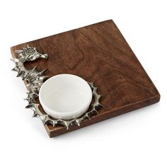 a white bowl sitting on top of a wooden tray next to a silver cup and saucer