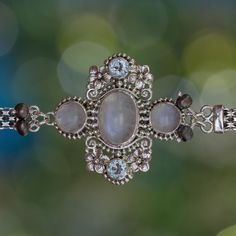 Exquisite details are evident in this stunning bracelet. Buana's design is escorted by blue-green peacock pearls, the pendant is studded with rainbow moonstone and blue topaz. Sterling Silver, Rainbow Moonstone, Blue Topaz, & Cultured Freshwater Pearl Panther Link chain Toggle clasp Combination finish 7-7.5" L Gemstone may have inclusions; this is normal and does not indicate a defect Handmade in & fairly traded from Indonesia Spiritual Silver Pearl Bracelet With Gemstone Beads, Bohemian Moonstone Bracelet, Bohemian Silver Moonstone Crystal Bracelet, Elegant Labradorite Bracelets For Gifts, Bohemian Moonstone Crystal Bracelet With Gemstones, Elegant Crystal Bracelet With Gemstone Beads And Moonstone, Elegant Moonstone Crystal Bracelet With Gemstone Beads, Elegant Moonstone Gemstone Beaded Bracelets, Elegant Moonstone Beaded Bracelets