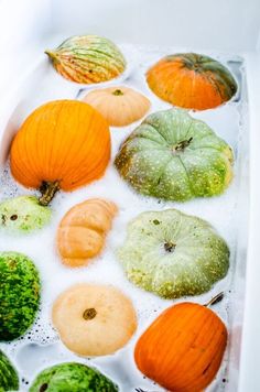 several pumpkins and gourds are in a tub of water with bubbles on the surface