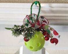 a green vase filled with christmas decorations on top of a white doorknott