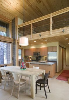 a dining room table with chairs and a kitchen area in the back ground, next to an open floor plan