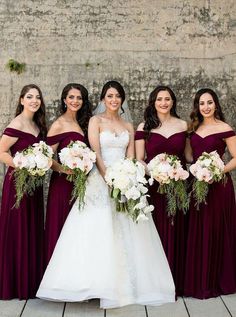 the bride and her bridesmaids pose for a photo in front of an old brick wall