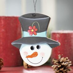 a snowman ornament hanging from a christmas tree with pine cones in the background