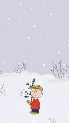 a little boy holding a small christmas tree in the middle of a snow covered field