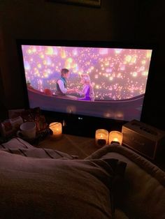 a person laying in front of a tv with candles on it