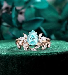 a ring with an aqua blue topazte surrounded by white and clear diamonds on a green velvet surface