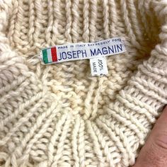 a close up of a person's hand holding a label on a white sweater