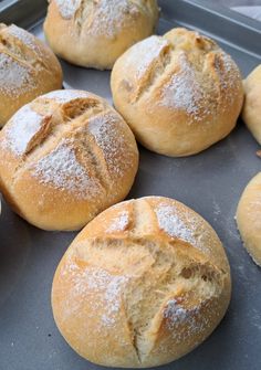 freshly baked breads sitting on top of a baking pan covered in powdered sugar