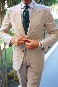 a man in a tan suit and green tie