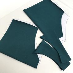 two pieces of green fabric sitting next to each other on top of a white surface