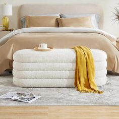 a white bed sitting on top of a wooden floor next to a pile of towels