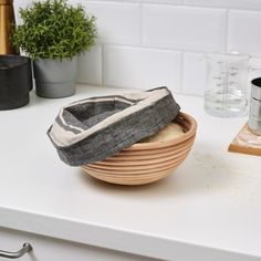 a wooden bowl sitting on top of a white counter next to a potted plant