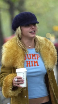 a woman walking down the street with a cup in her hand