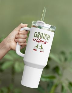 a person holding a white coffee cup with the words grinch vibes on it