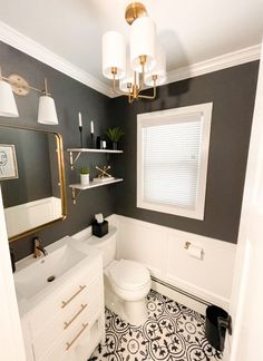 a white toilet sitting next to a sink under a window in a bathroom with black and white floor tiles