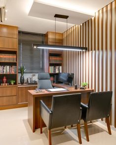 an office with two desks and chairs in front of a book shelf filled with books