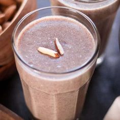 two glasses filled with smoothie next to cinnamon sticks