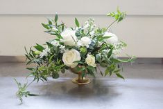 a vase filled with white flowers and greenery