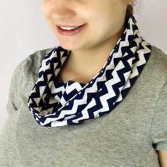 a woman wearing a gray shirt with a black and white chevron scarf around her neck