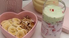 a heart shaped container filled with yogurt and banana slices next to a bowl of granola