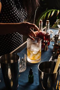 a woman is making an alcoholic cocktail at a bar