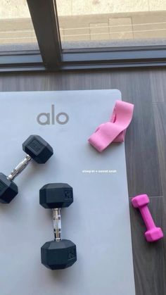 dumbbells and exercise mats on the floor in front of a window with an alo sign