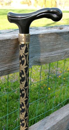 an ornate black and gold handlebar on a wooden fence with green grass in the background