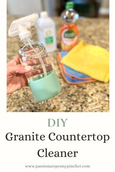 a hand holding a bottle filled with liquid and cleaning supplies on top of a counter