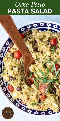 pasta with tomatoes, olives and parsley in a blue and white bowl next to a wooden spoon