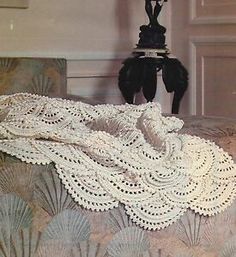 there is a crocheted blanket on top of a bed with shells around it